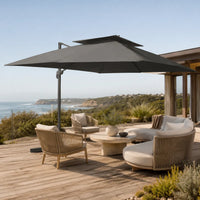 Levant XL anthracite cantilever umbrella shading a timber deck lounge area overlooking an Australian coastal landscape