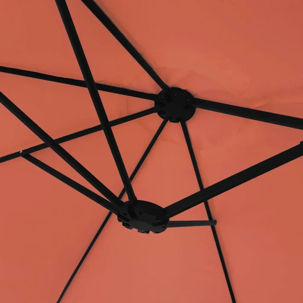 Underside view of a terracotta double canopy market umbrella showing black metal rib frame and dual hub junction