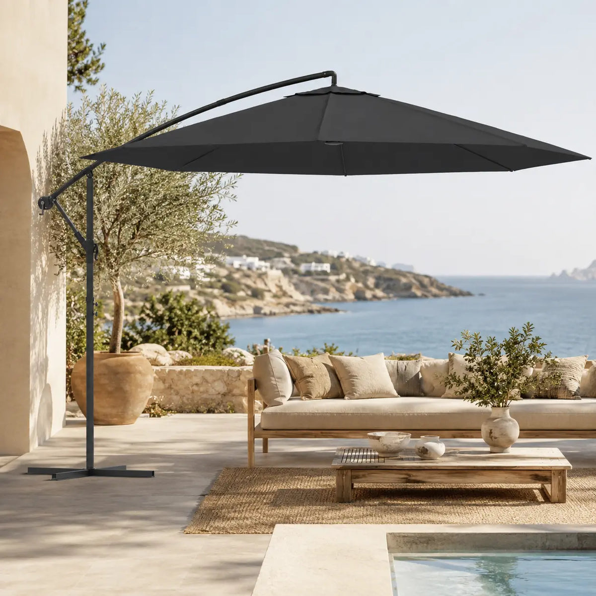 Round cantilever umbrella 3.5m Black over outdoor sofa on villa patio with pool and olive tree – Ostro