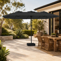 4.5m anthracite double canopy market umbrella shading a wicker outdoor dining table in a garden alfresco setting